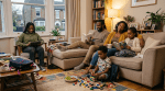 A family with two parents and three children reading and playing in a living room.